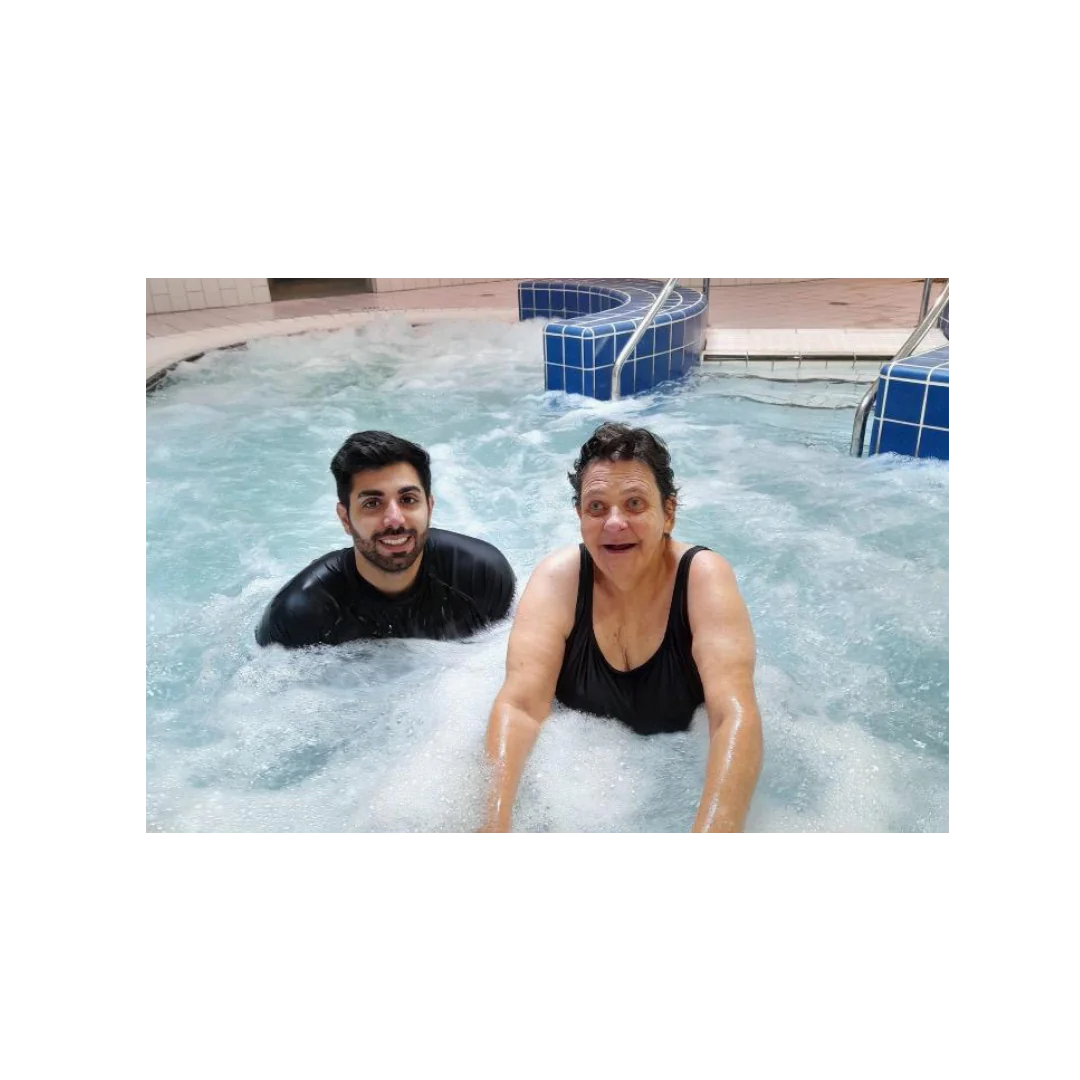 Physiotherapist and client smiling during a hydrotherapy session in an indoor pool