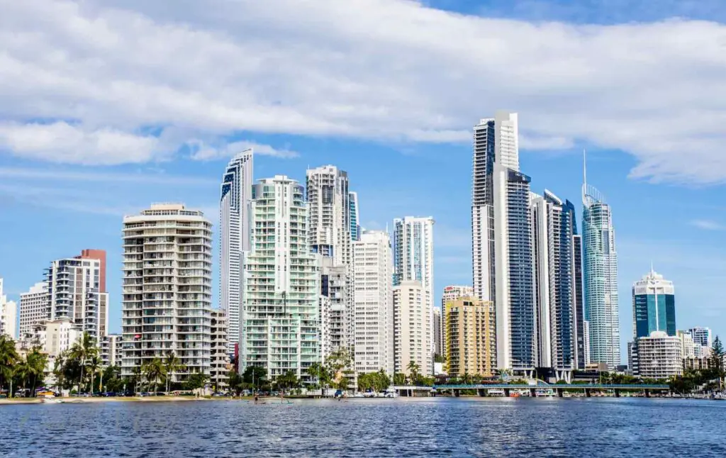Skyline of Surfers Paradise, QLD, featuring high-rise buildings along the waterfront, with a clear blue sky and the Nerang River in the foreground. Perfectly suited for promoting urban mobile physiotherapy services in a vibrant, high-density coastal suburb.