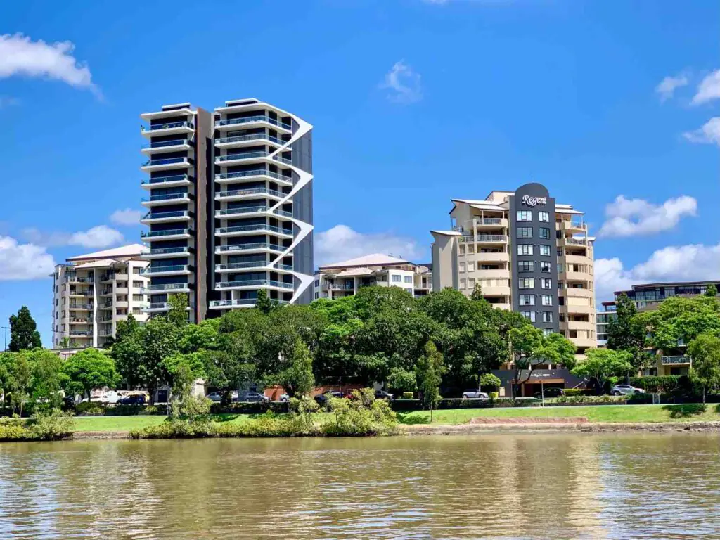 Modern riverside apartment buildings in Toowong, Brisbane, viewed from across the Brisbane River on a sunny day—ideal for showcasing mobile physiotherapy services available in the Toowong area.