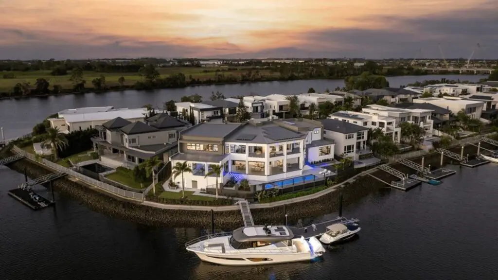 Luxury waterfront homes in Hope Island, Gold Coast, at sunset with private jetties and moored yachts along the canal.