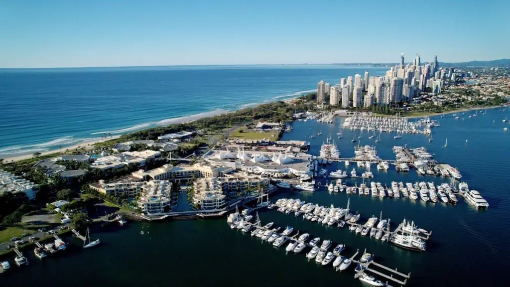 Aerial view of Main Beach and the Southport Marina in the Gold Coast, showing luxury waterfront apartments, yachts, and the Pacific Ocean coastline stretching into the distance.