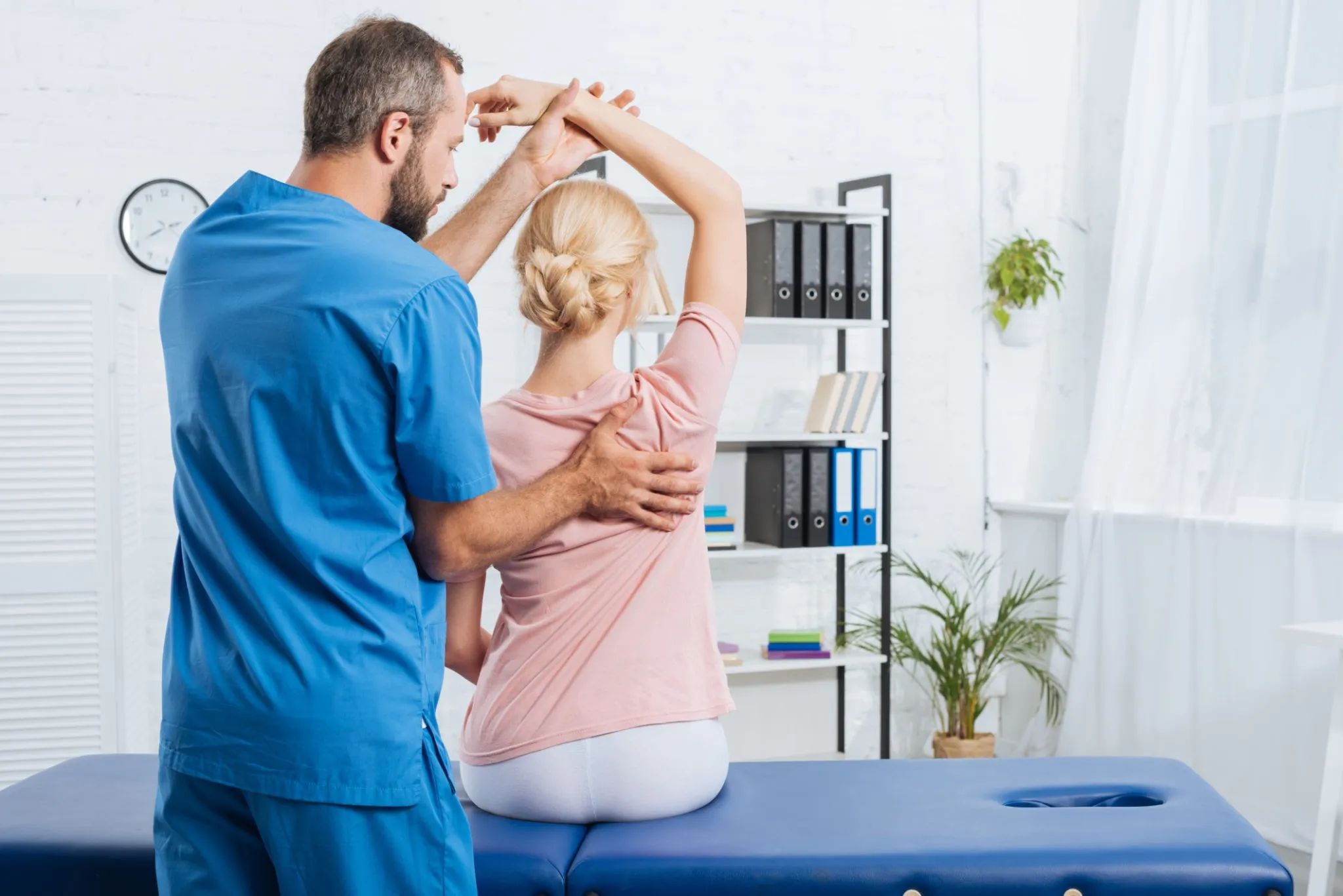Professional physiotherapist treating a patient recovering from injury, showing hands-on therapy technique in a comfortable home setting.
