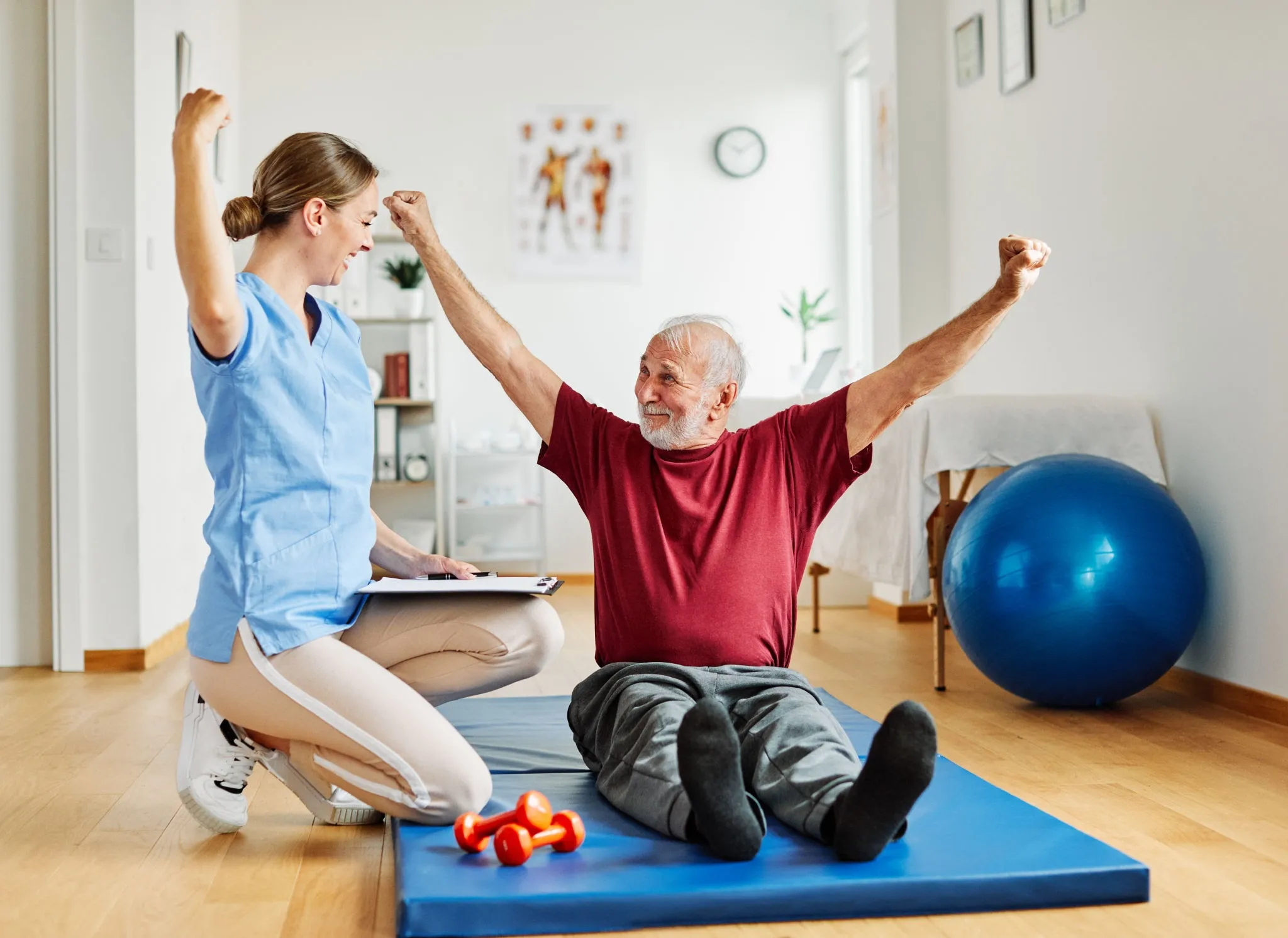 Professional physiotherapist working with a senior in their home, helping with gentle movement exercises.