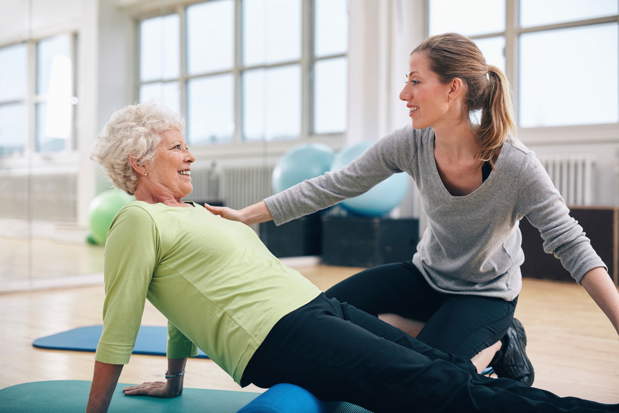 Senior Woman Doing Hip Exercises with Physiotherapist at Home