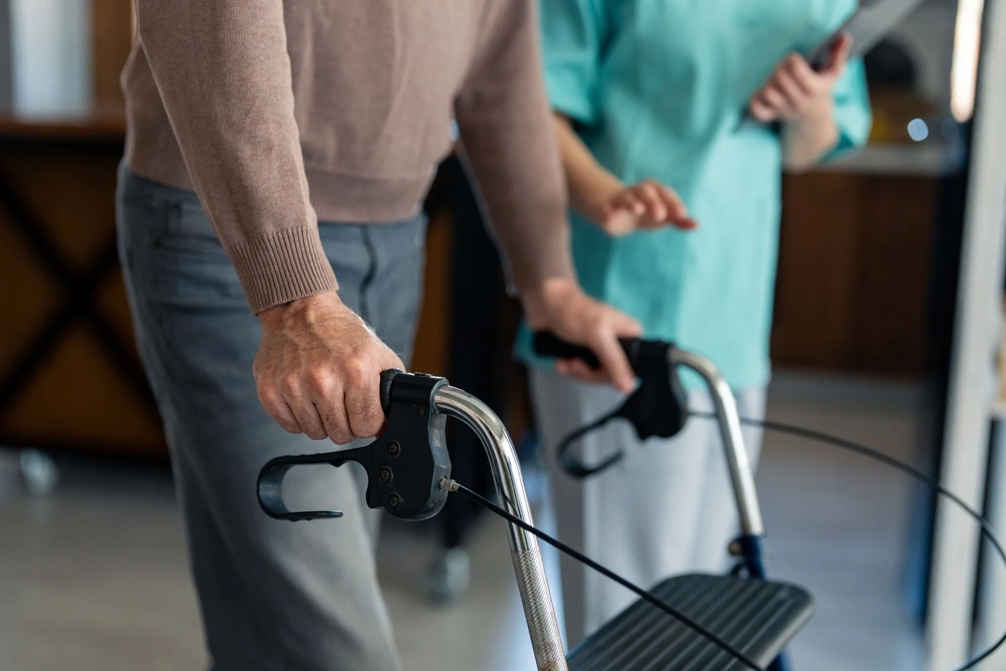 Elderly person using walking aid with physiotherapist guidance in comfortable home environment