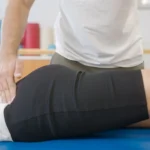Physiotherapist guiding a client through a simple sciatica exercise at home image