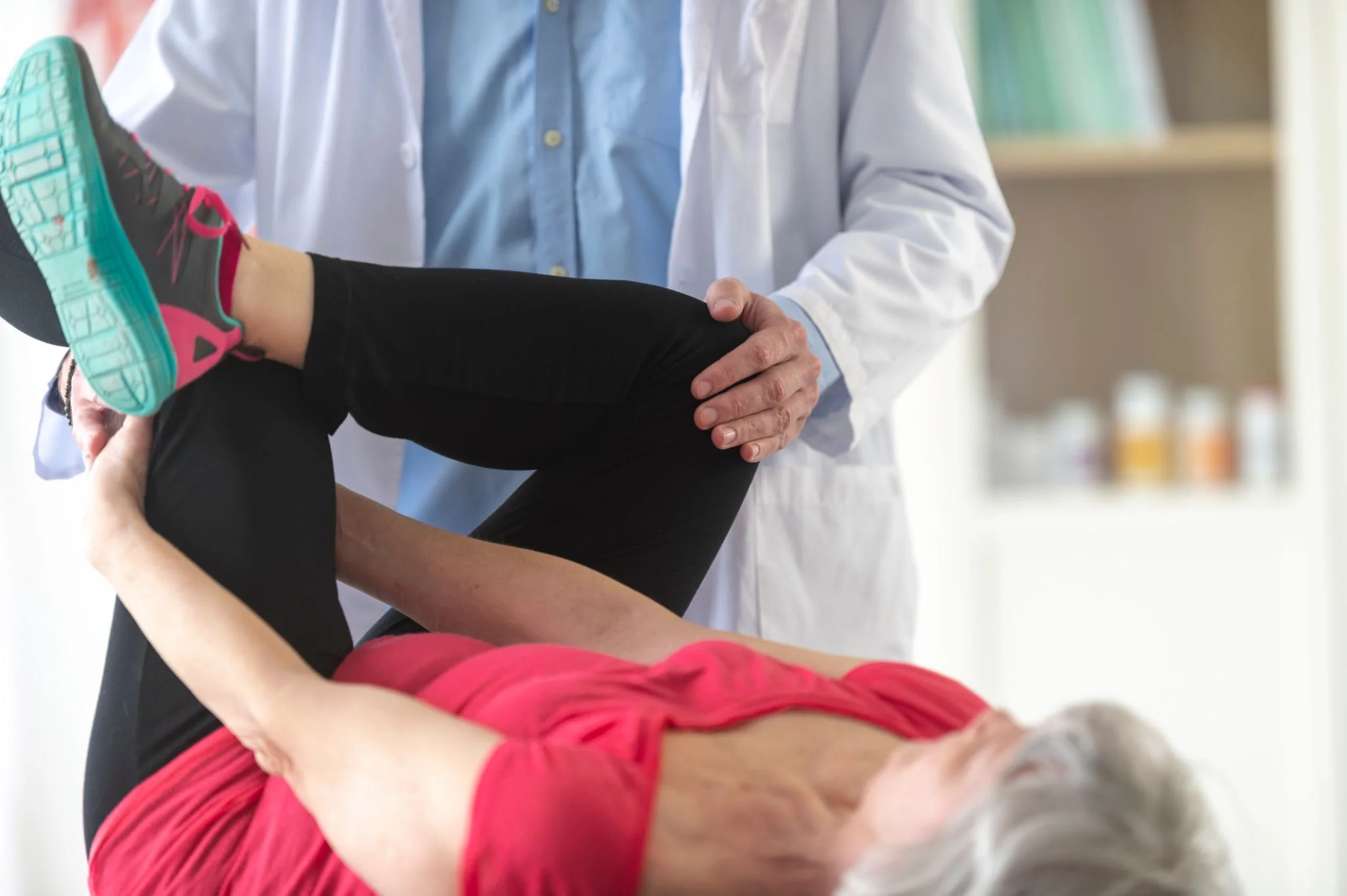 Physiotherapist guiding a client through a simple sciatica exercise at home.