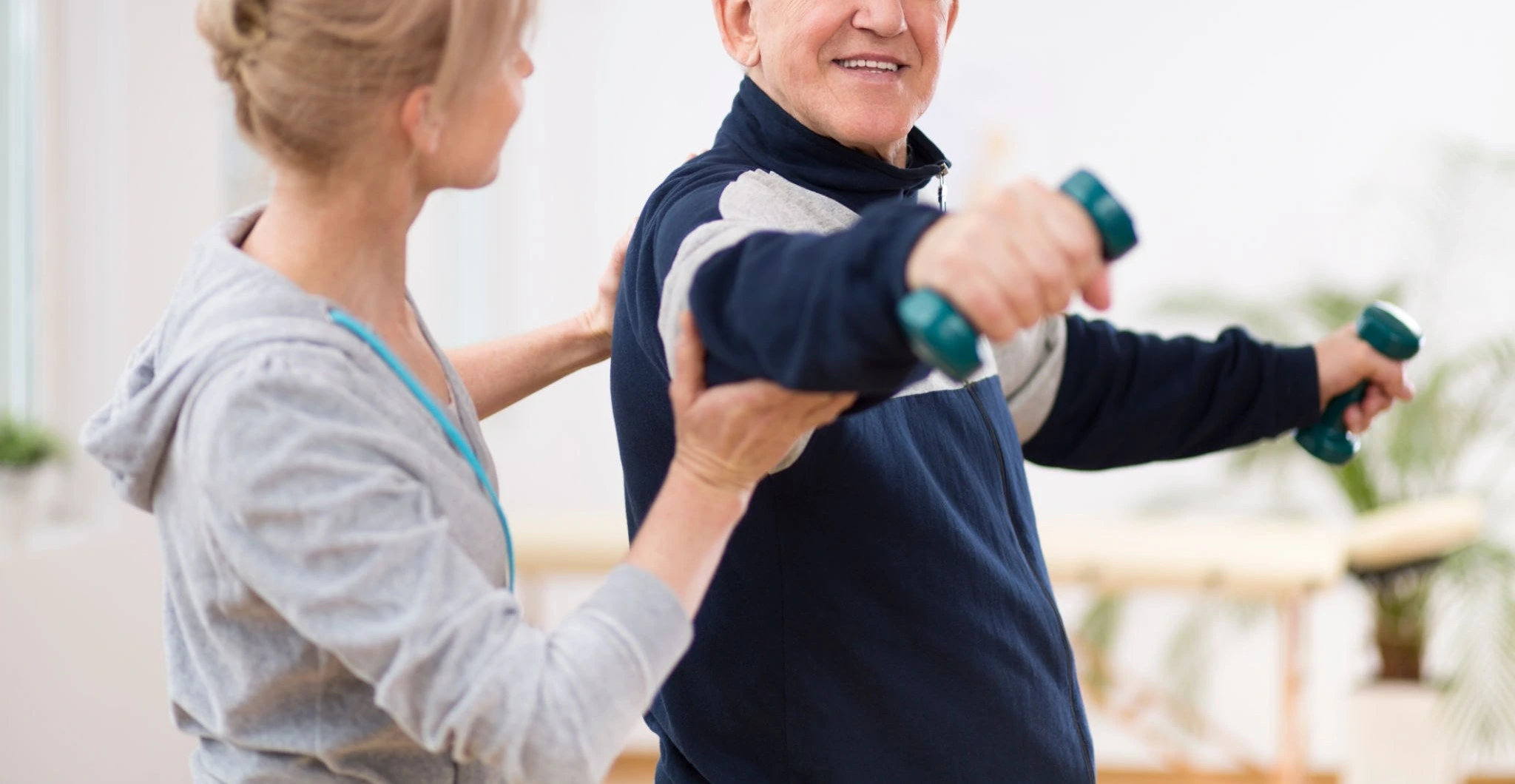Physiotherapist helping a senior patient with osteoporosis exercises at home