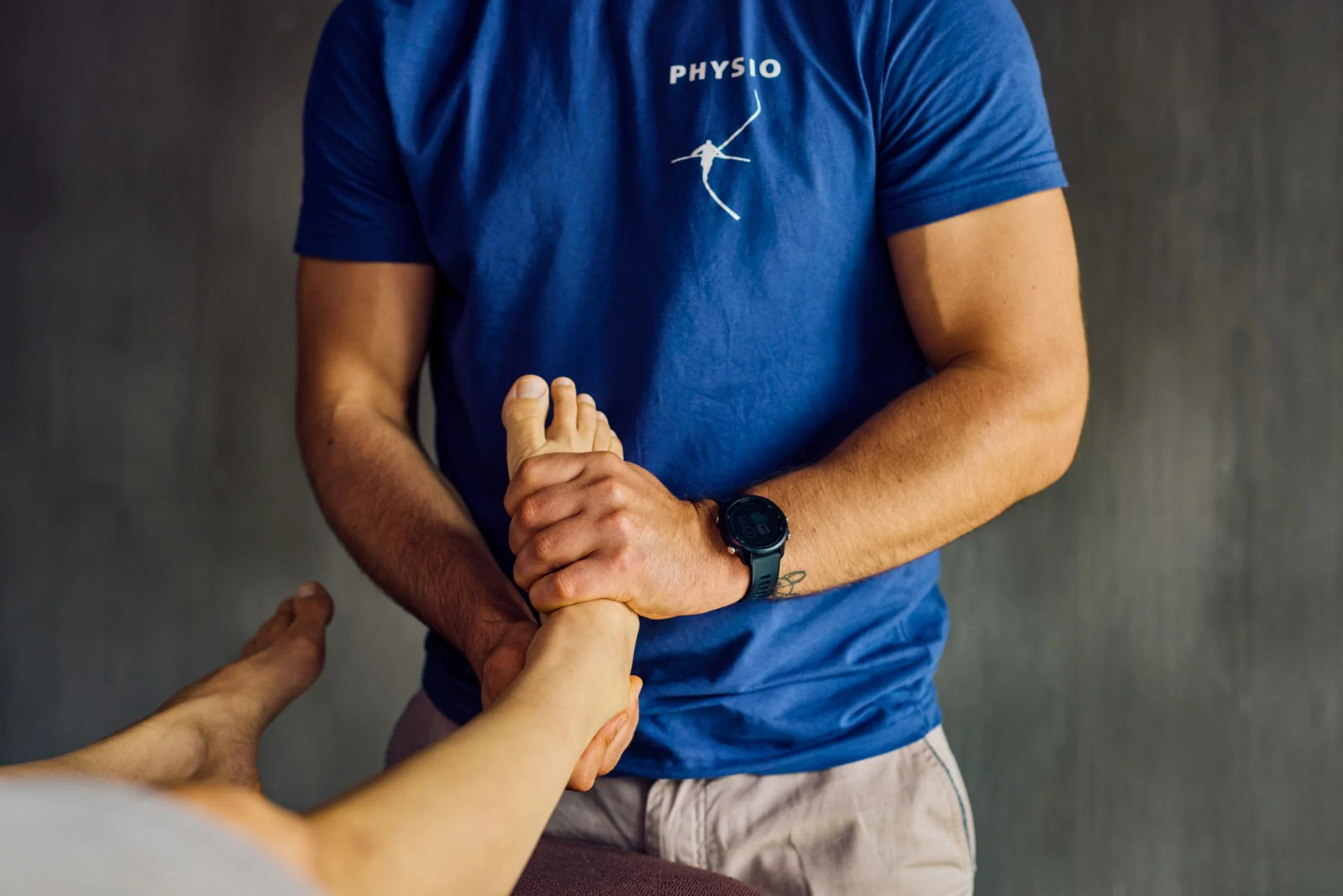 Physiotherapist working with athlete, hands-on treatment visible, home or training facility setting. Shows professional care and athlete engagement.